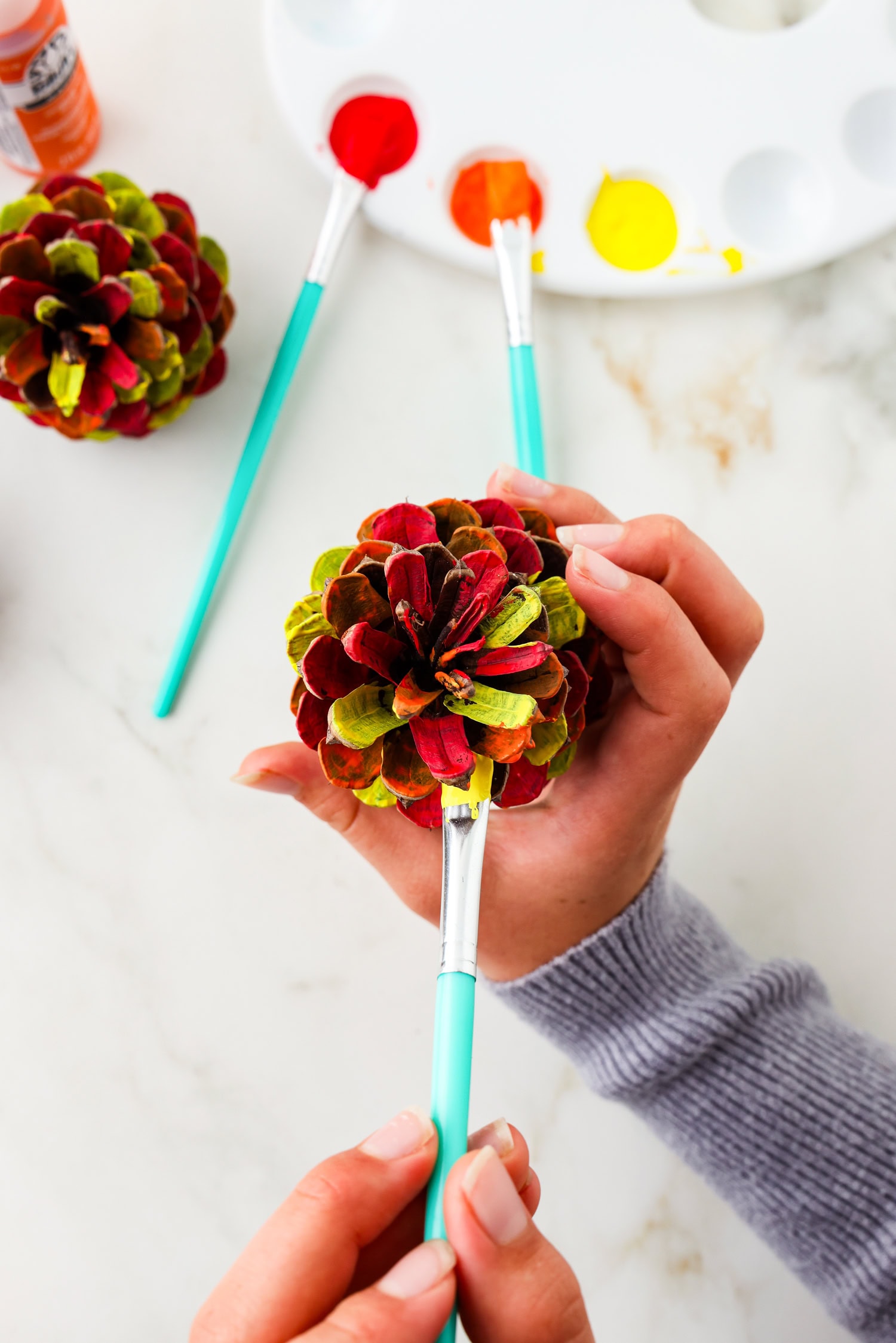 Picture of painting red and yellow on pinecone.