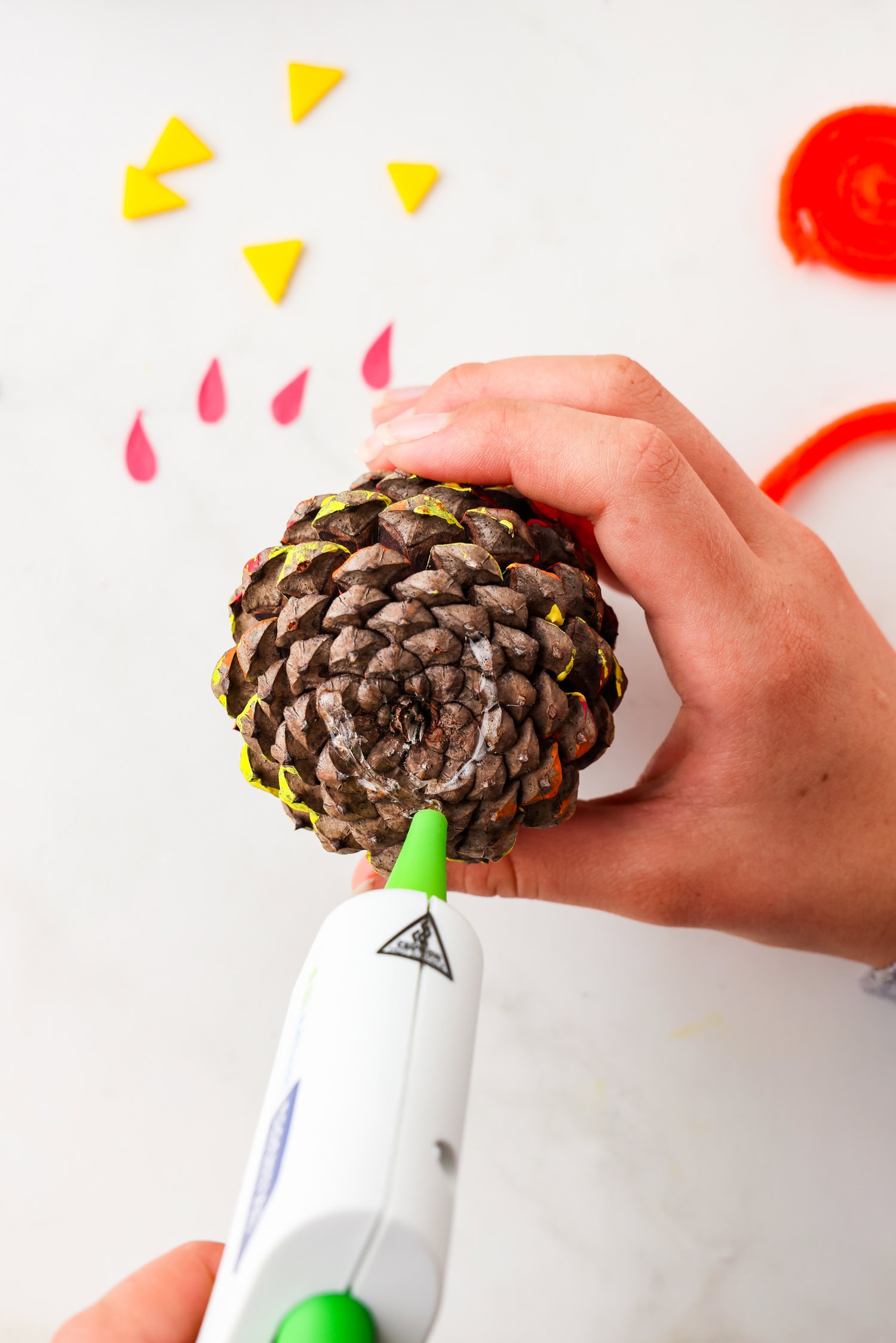 Picture of glue being placed on the bottom of the pinecone turkey.