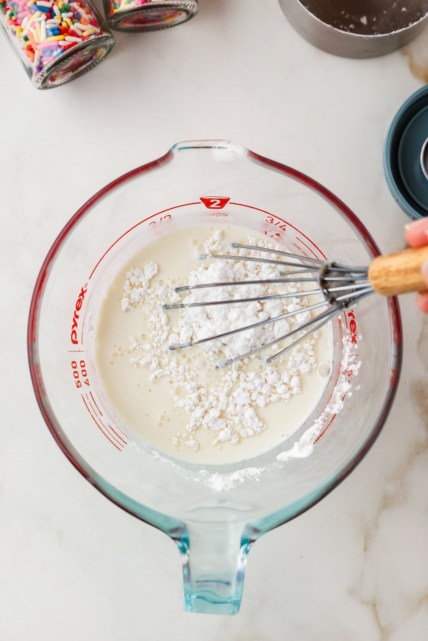 Whisk mixing the powdered sugar and heavy cream together.