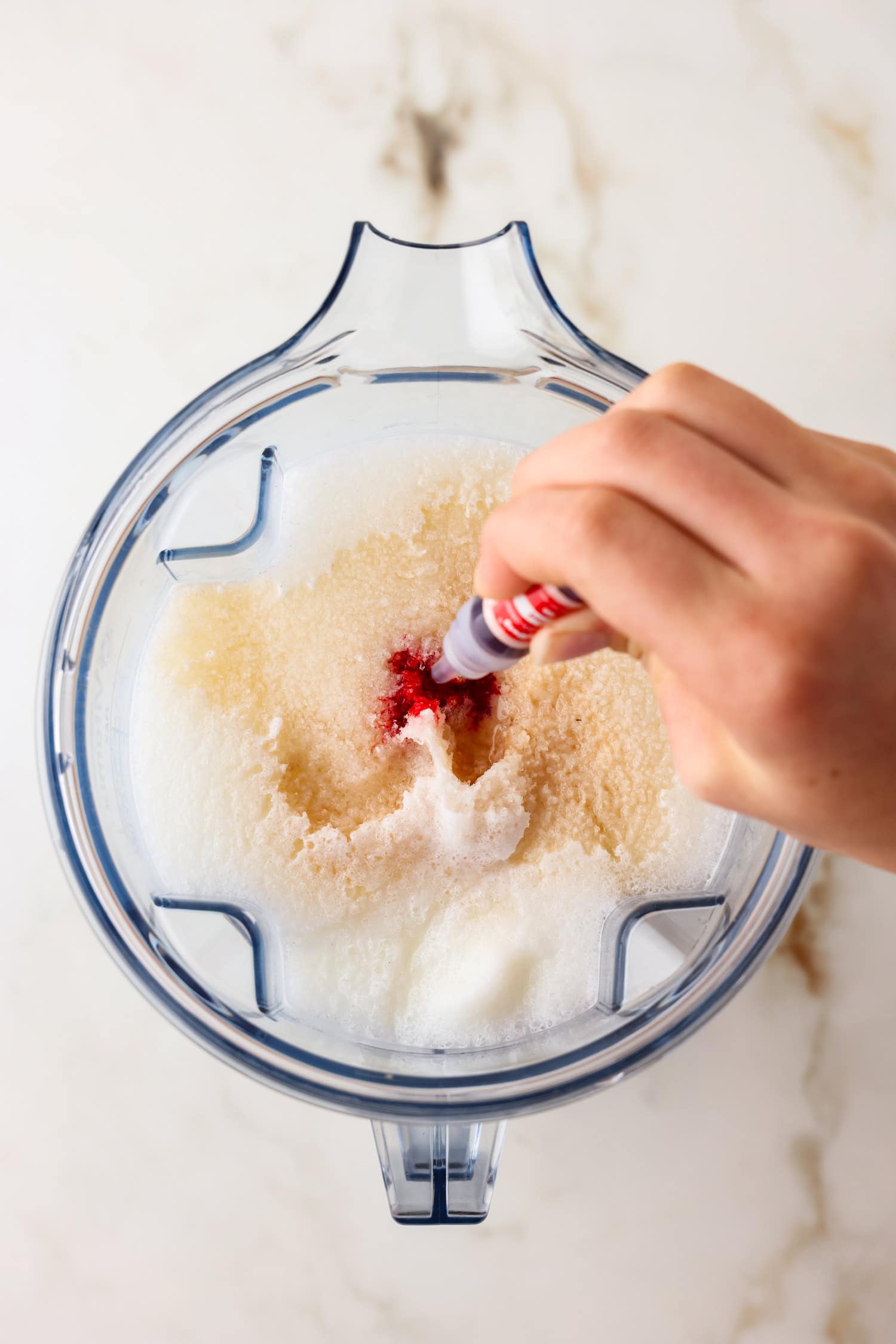 Overhead picture of strawberry flavor being added to snow ice cream in the blender.