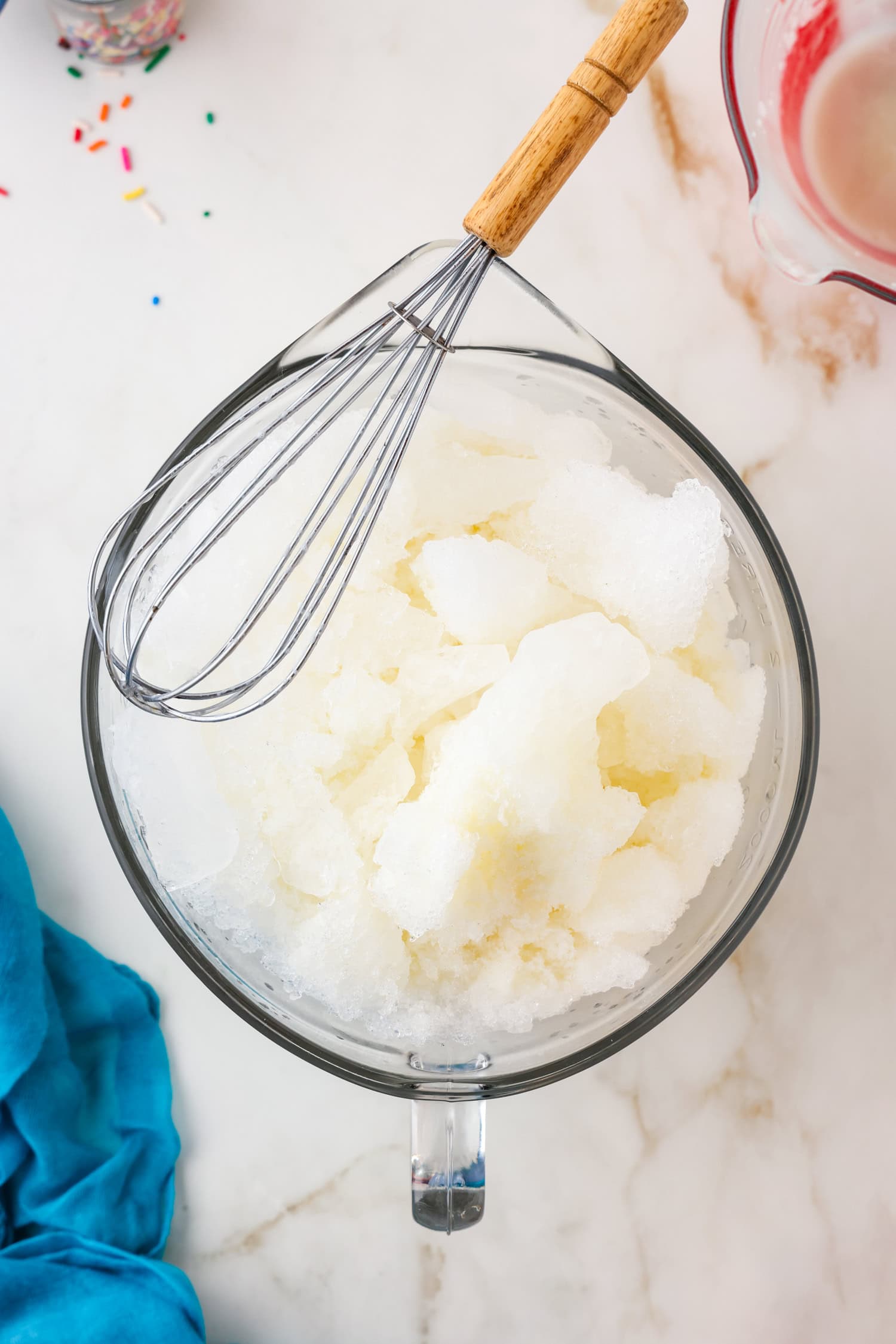 Whisk with snow ice cream ingredients in a glass bowl unmixed.