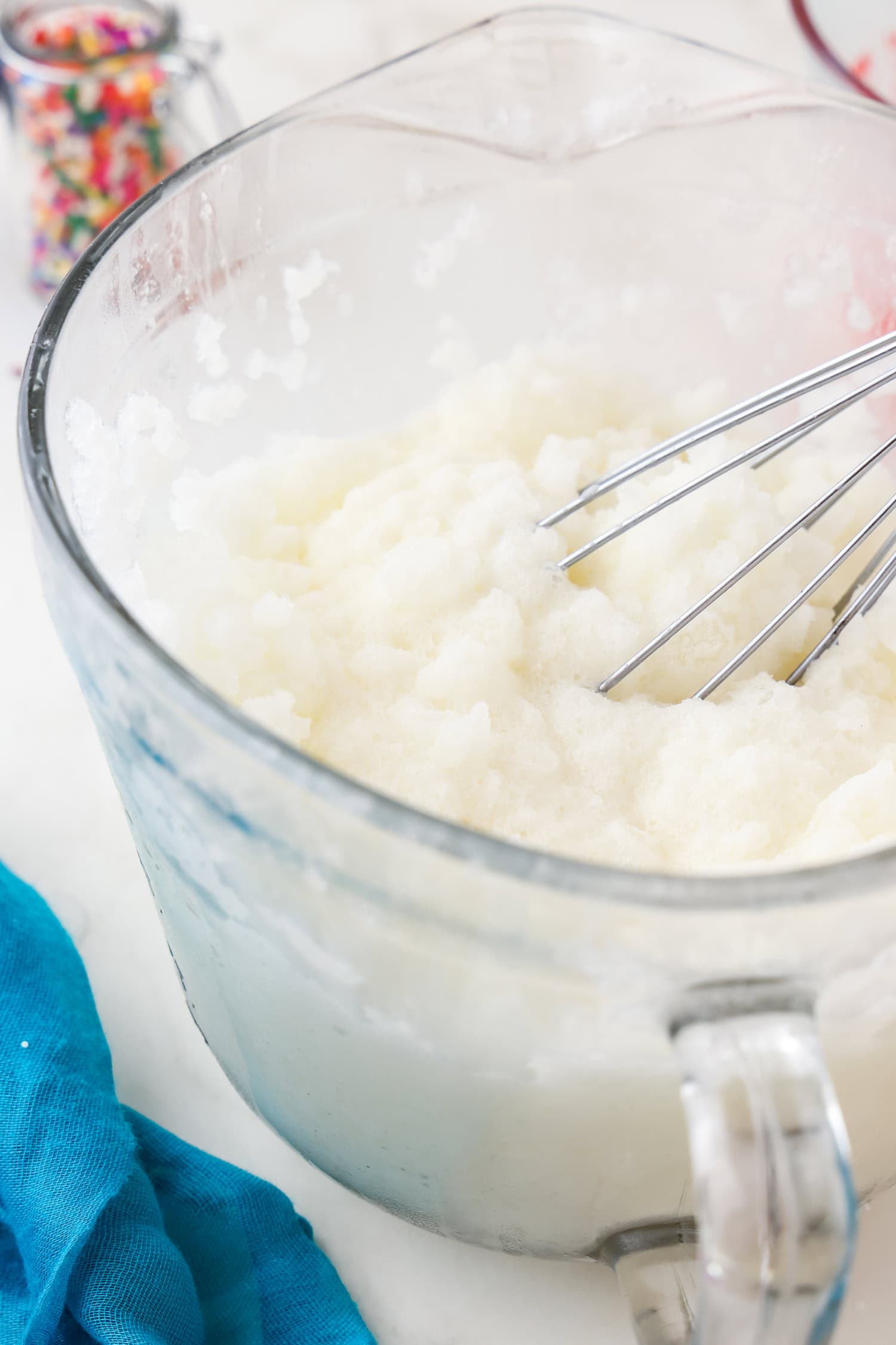 Close up picture of whisk with snow ice cream ingredients in a glass bowl mixed.