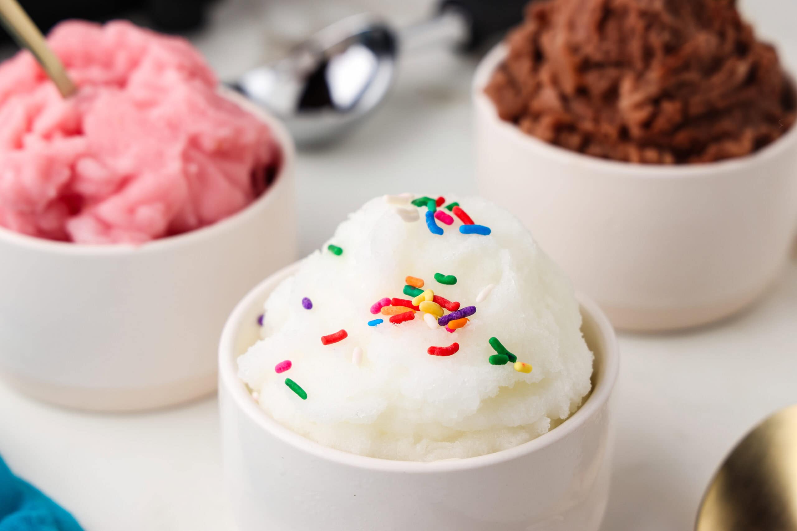 Picture of chocolate, vanilla and strawberry snow ice cream in white dishes.
