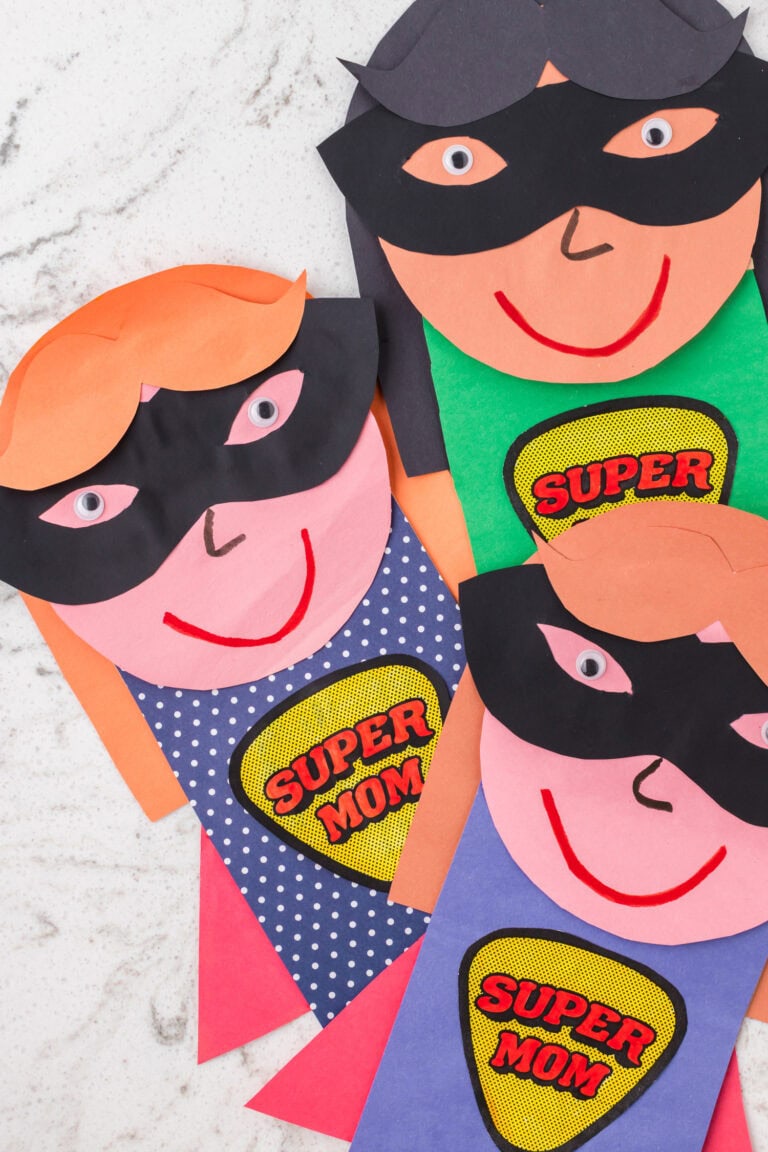 Two completed paper superhero crafts with “Super Mom” badges on their shirts.
