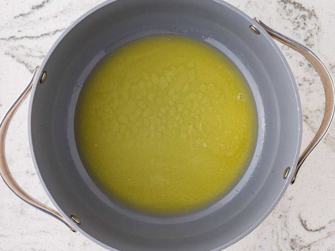 Overhead view of a large saucepan filled with melted butter, ready for making rainbow Rice Krispies treats.