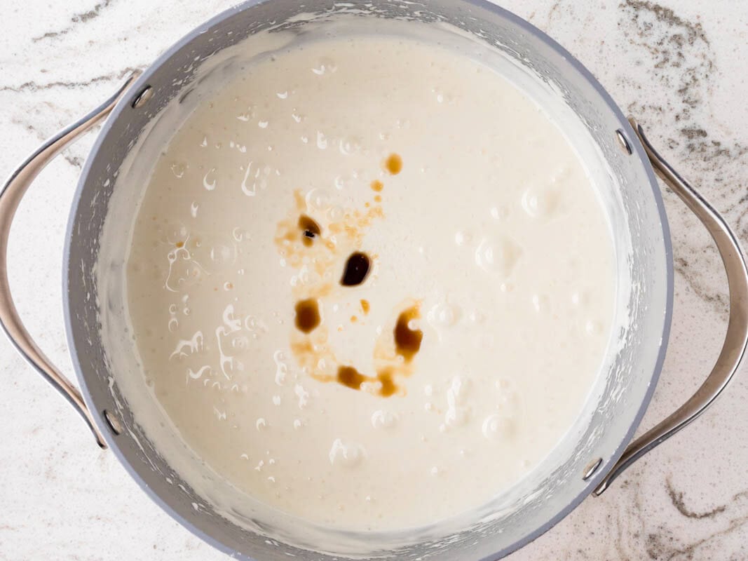 Creamy melted marshmallow mixture with vanilla extract in a saucepan, prepared as the base for colorful Rice Krispies treats.