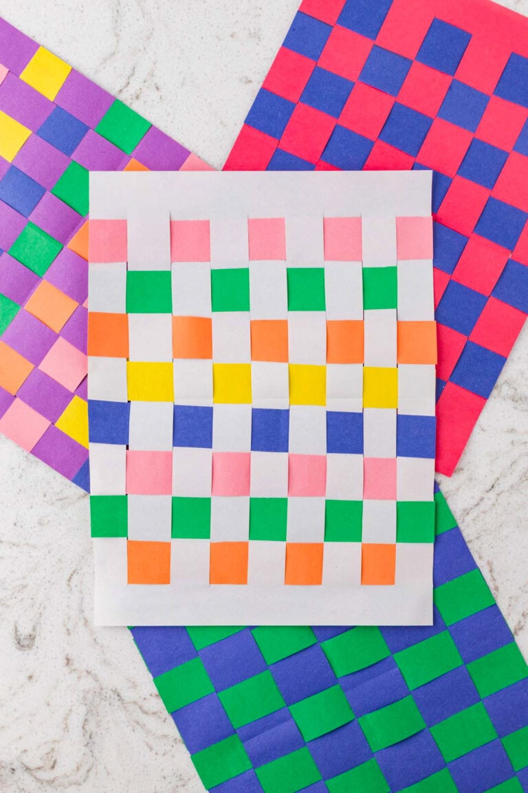 Finished paper weaving crafts in various color combinations displayed together, showing completed woven checkerboard patterns.
