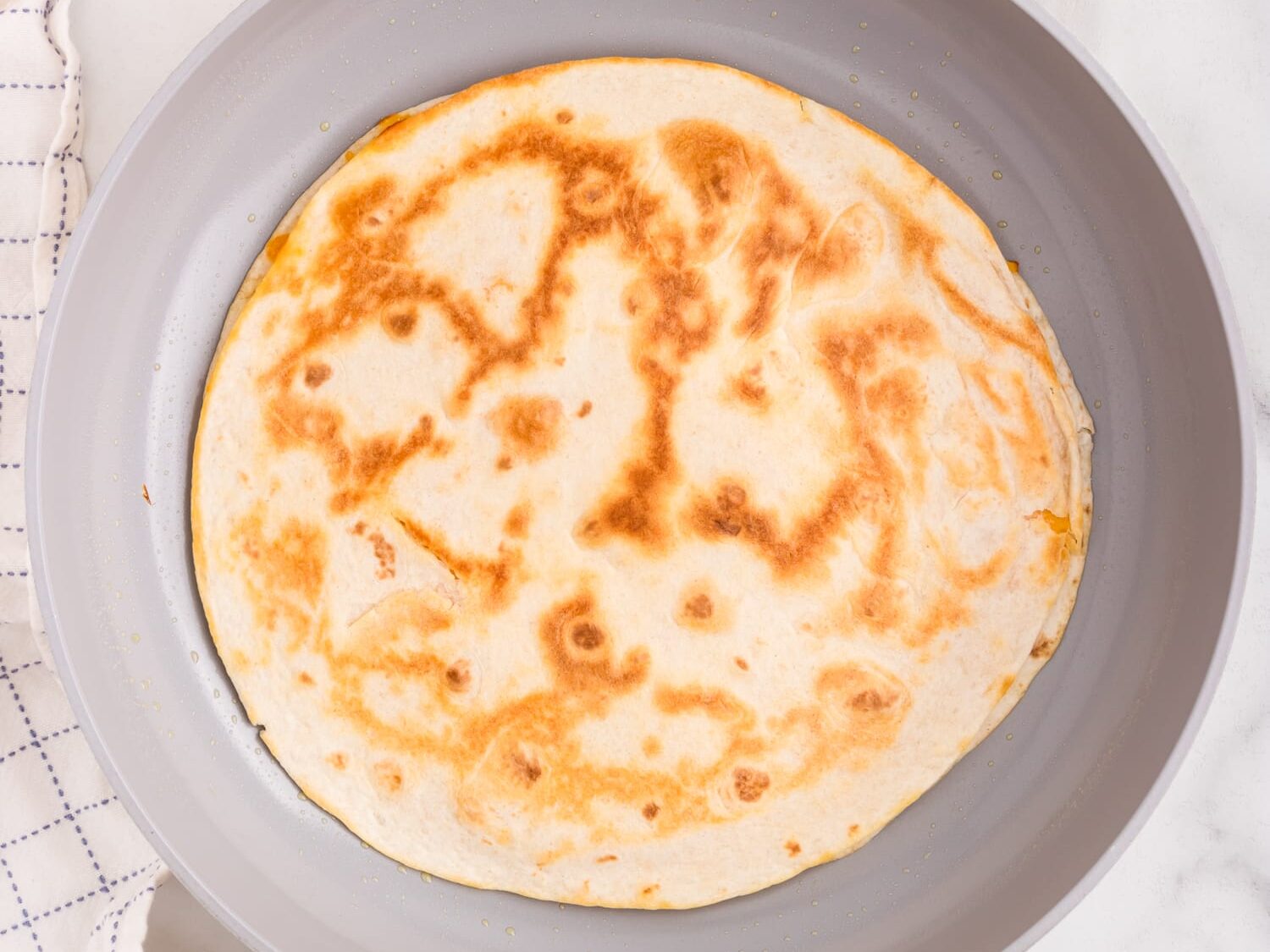 Cheese Quesadilla flipped in the skillet to reveal the golden brown