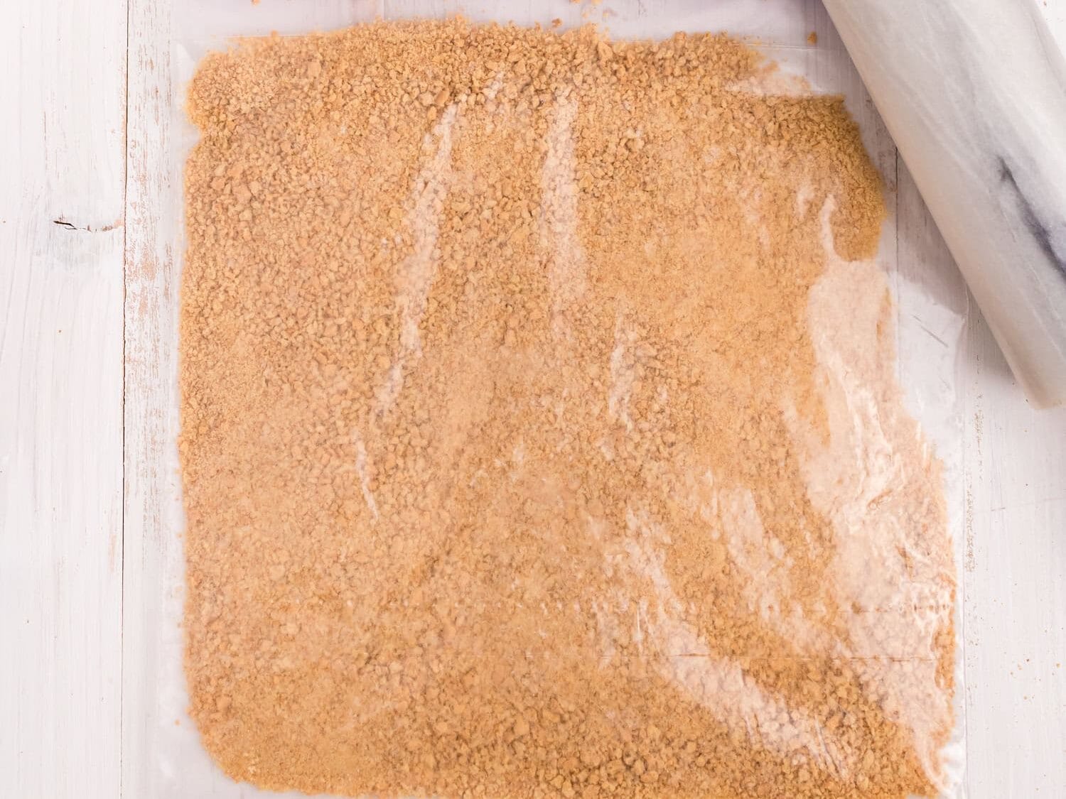 Crushing graham crackers for crust base with rolling pin in large zip lock bag