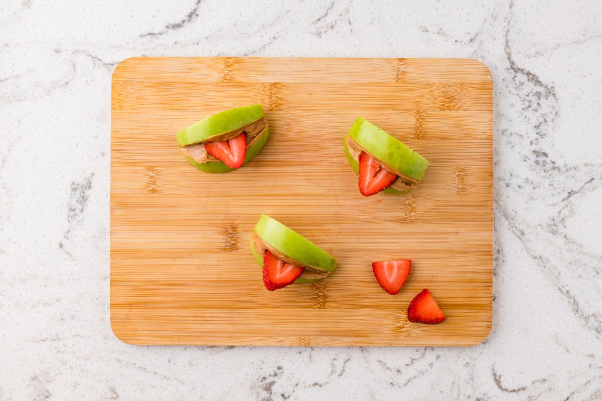 Fresh strawberry slices tucked between peanut butter-covered apple wedges to create the tongues for Halloween apple monsters.