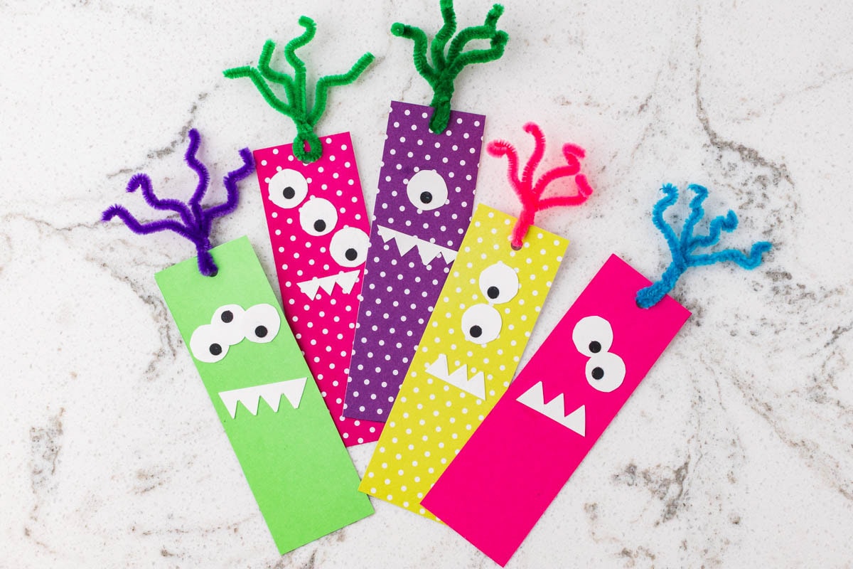Five colorful handmade monster bookmarks decorated with googly-style eyes, paper teeth, and pipe cleaner tentacles.